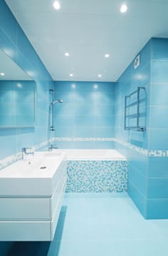 A bathroom with blue tile and white fixtures.