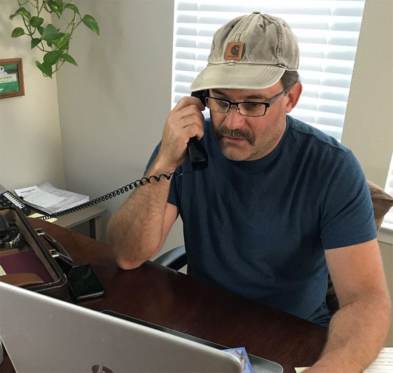 A man sitting at his desk on the phone.