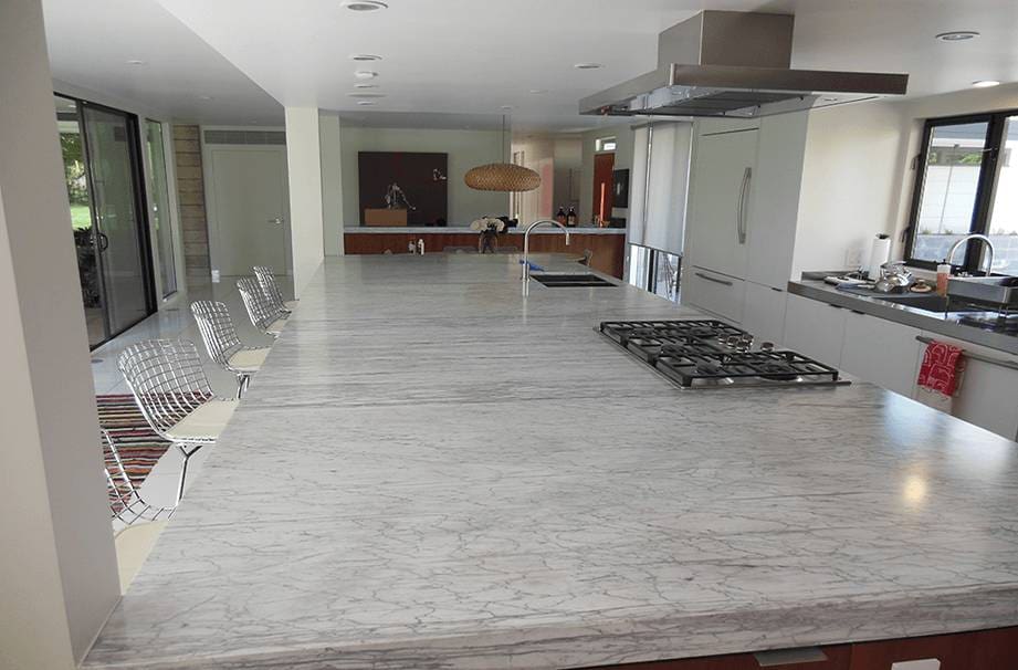 A large kitchen with white marble counters and a stove.