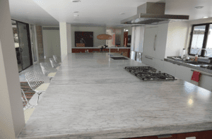 A large kitchen with marble counter tops and white cabinets.